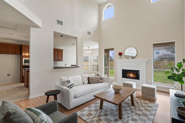 living room with light wood-style flooring, baseboards, visible vents, and a premium fireplace