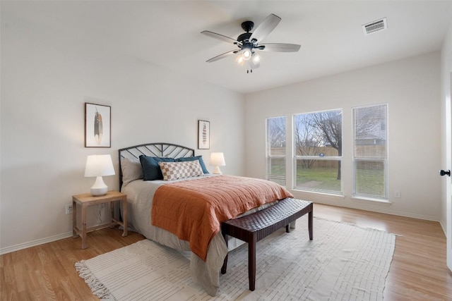 bedroom with light wood-type flooring, visible vents, baseboards, and ceiling fan