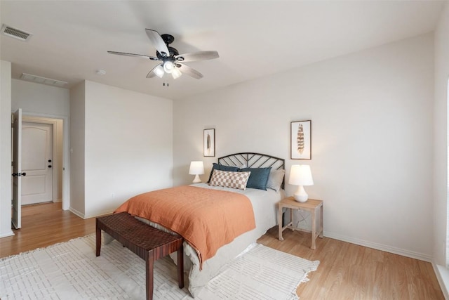 bedroom featuring ceiling fan, light wood-style floors, visible vents, and baseboards