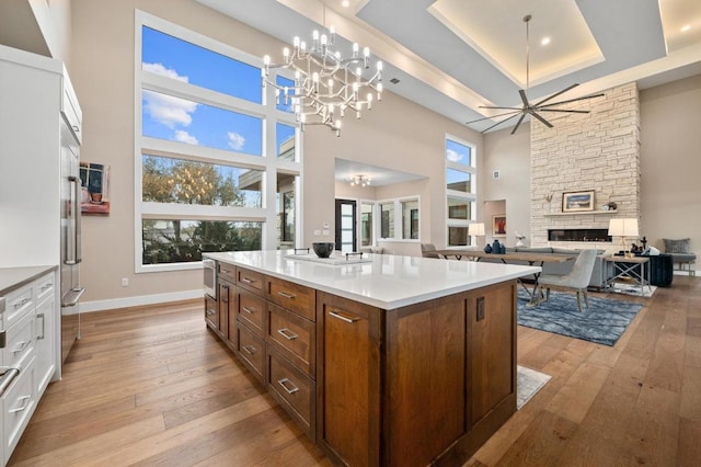 316 Duckhorn Pass, Austin, TX 78738 - kitchen with light wood finished floors, a towering ceiling, a chandelier, a fireplace, and white cabinetry
