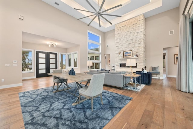316 Duckhorn Pass, Austin, TX 78738 - dining area with a towering ceiling, light wood-type flooring, french doors, and a stone fireplace