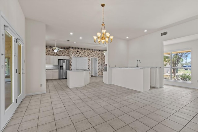 25048 River Rd, Spicewood, TX 78669 - kitchen featuring stainless steel fridge with ice dispenser, a chandelier, decorative light fixtures, light stone countertops, and recessed lighting