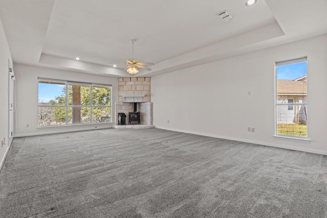 25048 River Rd, Spicewood, TX 78669 - unfurnished living room with a raised ceiling, carpet, recessed lighting, a ceiling fan, and a stone fireplace