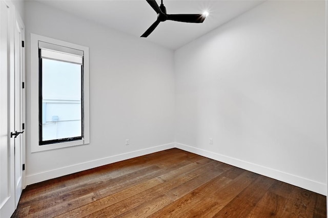 empty room with dark wood finished floors, a ceiling fan, and baseboards