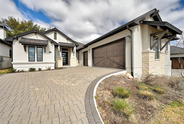 view of front facade with a garage, stone siding, and stucco siding