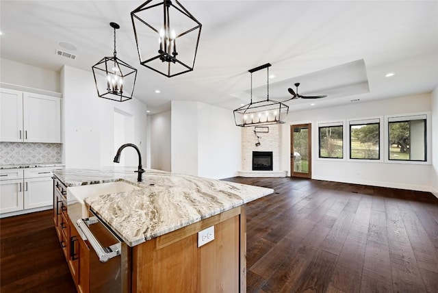 kitchen featuring light stone countertops, visible vents, dark wood finished floors, a notable chandelier, and open floor plan