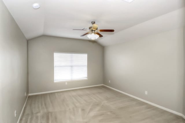 unfurnished room featuring baseboards, light colored carpet, a ceiling fan, and vaulted ceiling