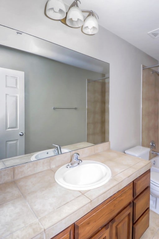 bathroom featuring vanity, shower / tub combination, toilet, and visible vents