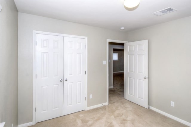 unfurnished bedroom featuring baseboards, visible vents, a closet, and light carpet