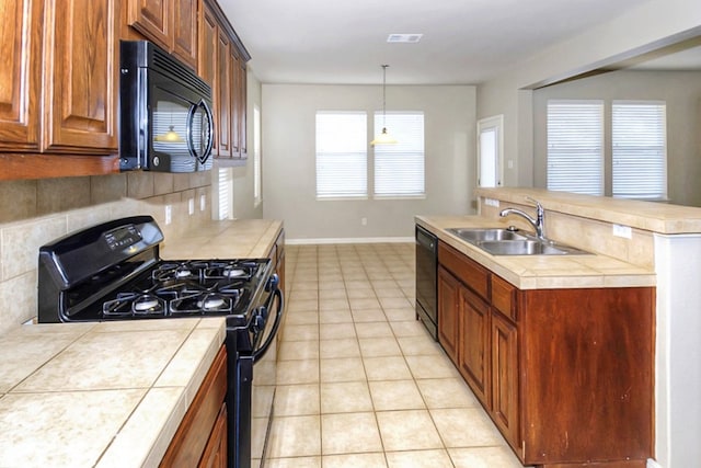 kitchen with tile countertops, light tile patterned floors, a sink, black appliances, and backsplash