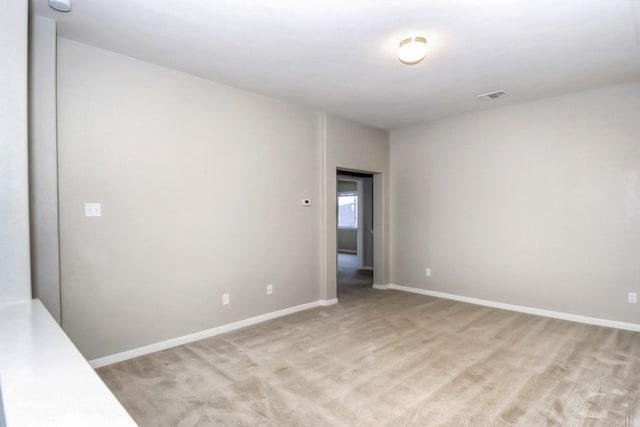 empty room with light colored carpet, baseboards, and visible vents