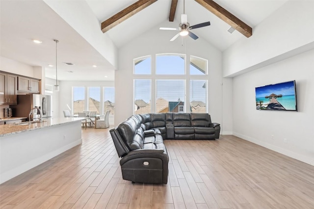 living area with baseboards, beamed ceiling, high vaulted ceiling, and light wood-style floors