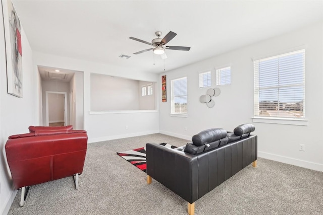 carpeted living area with baseboards, visible vents, attic access, and a ceiling fan