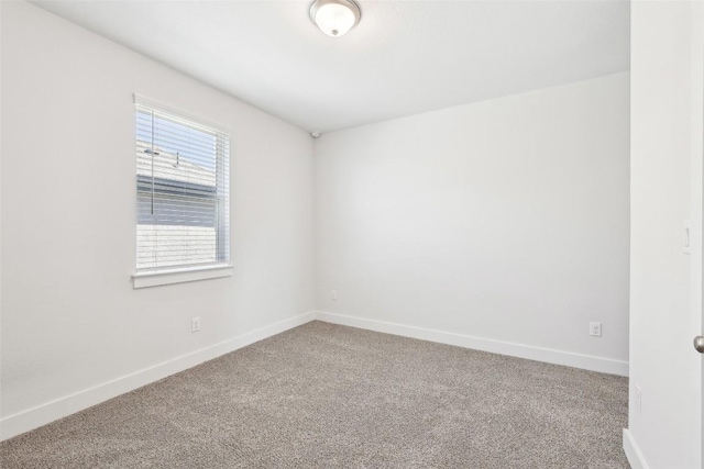 empty room featuring carpet and baseboards