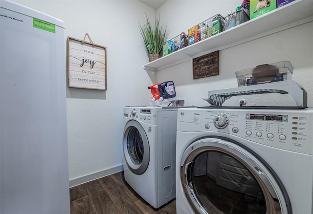 washroom featuring laundry area, washing machine and dryer, dark wood-style flooring, and baseboards