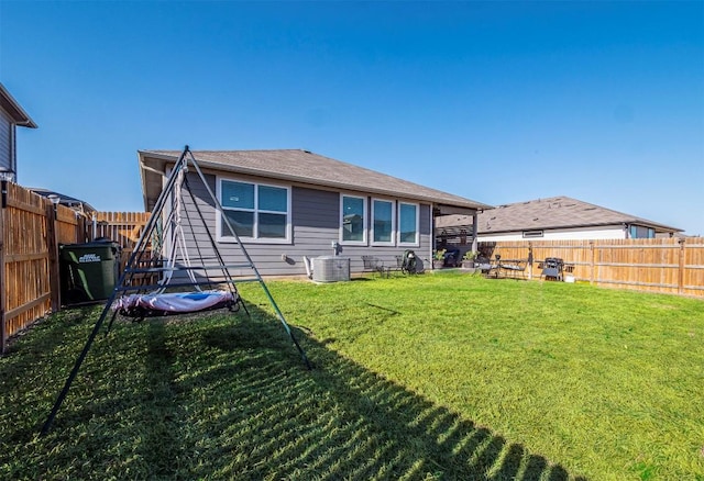 rear view of property with a yard, central AC unit, and a fenced backyard