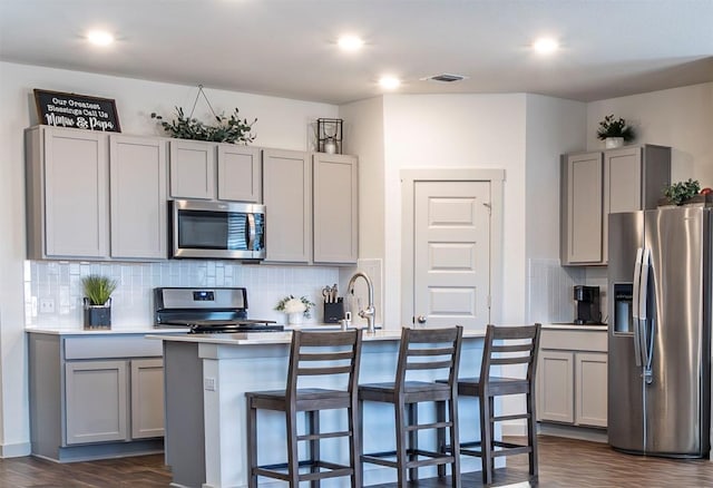 208 Greens Bayou Trl, Hutto, TX 78634 - kitchen featuring appliances with stainless steel finishes, gray cabinets, tasteful backsplash, dark wood-style floors, and recessed lighting