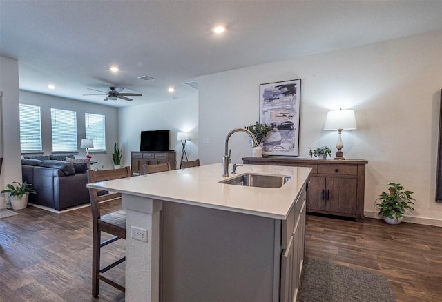 kitchen featuring a ceiling fan, visible vents, dark wood finished floors, a sink, and light countertops