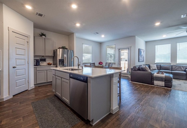 208 Greens Bayou Trl, Hutto, TX 78634 - kitchen featuring stainless steel appliances, gray cabinetry, open floor plan, dark wood-style flooring, and healthy amount of natural light