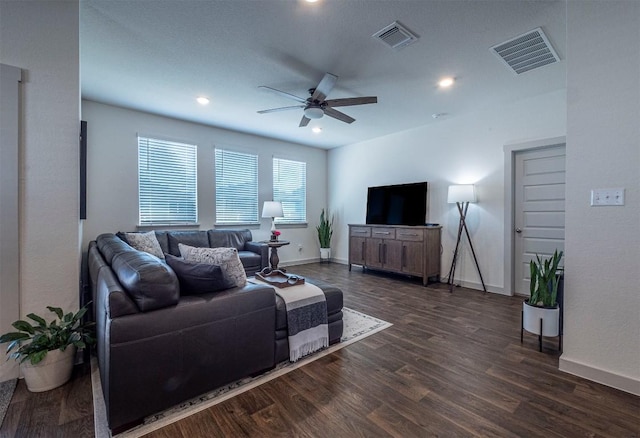 living area with visible vents, baseboards, dark wood-type flooring, and a ceiling fan