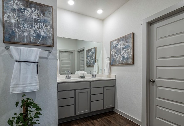 full bath with a sink, baseboards, wood finished floors, and double vanity