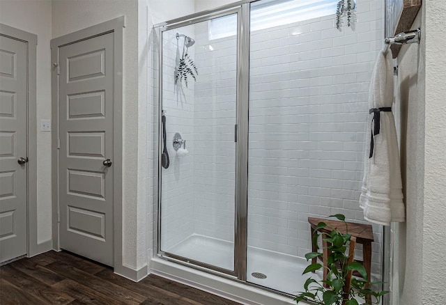 full bath with a shower stall, wood finished floors, and a textured wall