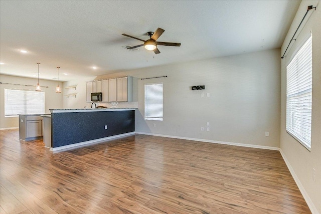 unfurnished living room with a ceiling fan, healthy amount of natural light, light wood-type flooring, and recessed lighting