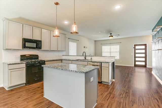 300 Eagle Lake Dr, Hutto, TX 78634 - kitchen with black appliances, a peninsula, dark wood-style floors, a kitchen island, and backsplash