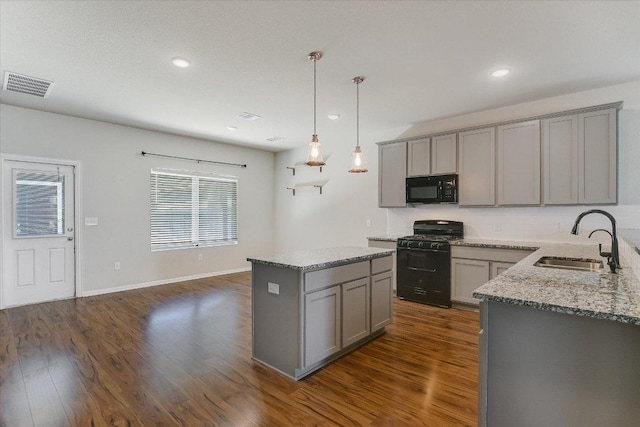 kitchen with black appliances, gray cabinetry, a sink, dark wood-type flooring, and light stone countertops