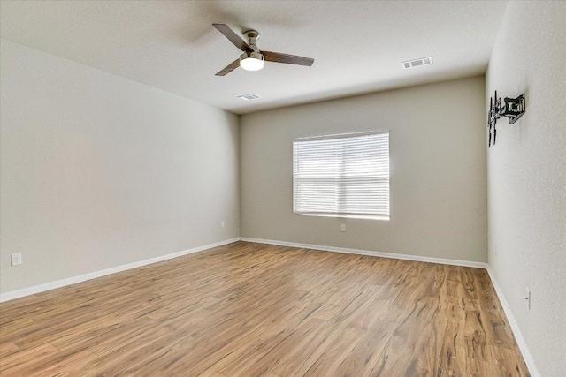 empty room with light wood-style floors, a ceiling fan, and baseboards