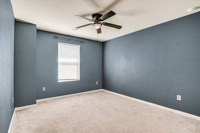 carpeted empty room featuring a ceiling fan, a smoke detector, a textured wall, and baseboards