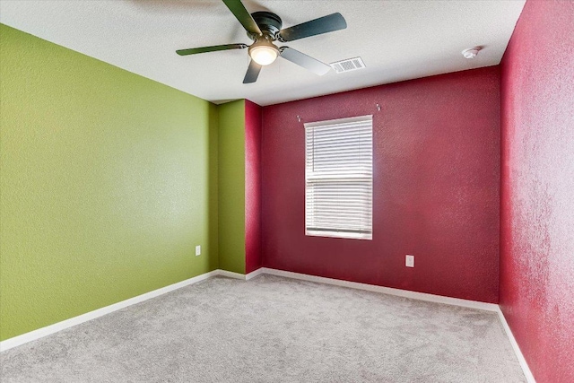 carpeted empty room featuring ceiling fan, a textured wall, baseboards, and a smoke detector