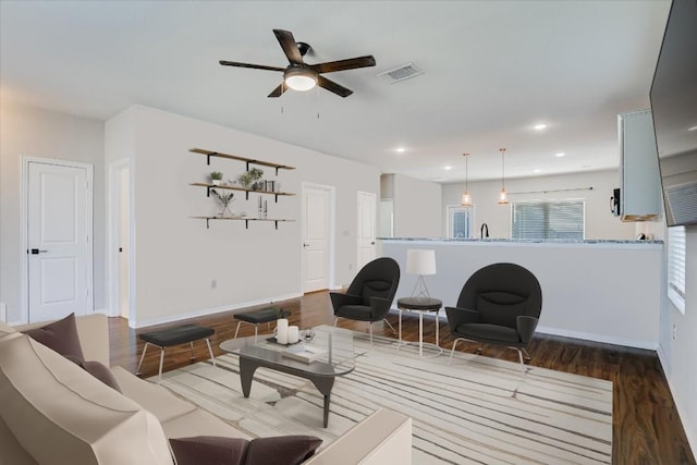 living area with wood finished floors, a ceiling fan, baseboards, and recessed lighting