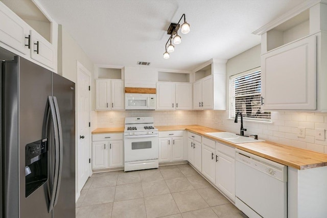 kitchen featuring butcher block countertops, white appliances, white cabinetry, and a sink