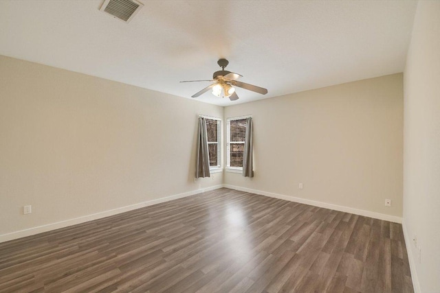 empty room with visible vents, baseboards, dark wood-type flooring, and a ceiling fan