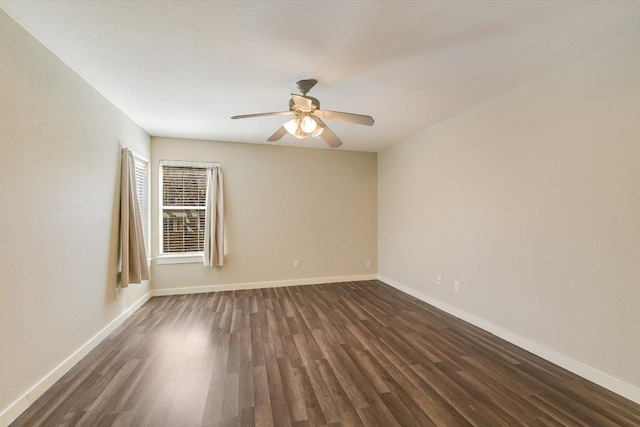 spare room with baseboards, a ceiling fan, and dark wood-style flooring