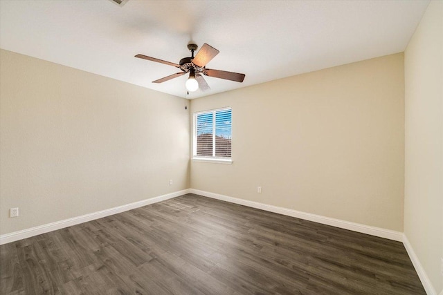 empty room featuring dark wood-type flooring, a ceiling fan, and baseboards