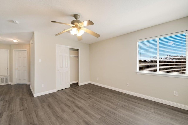 unfurnished bedroom featuring wood finished floors, visible vents, baseboards, ceiling fan, and a closet