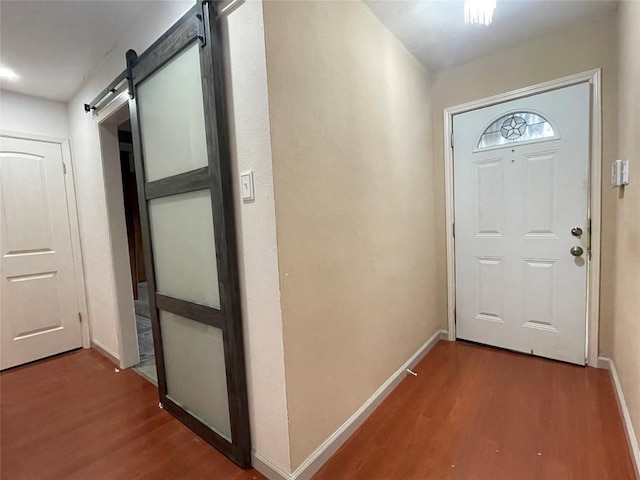 foyer entrance featuring baseboards, a barn door, and wood finished floors