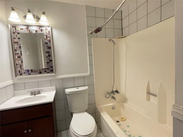 bathroom featuring tile walls, vanity, toilet, and bathing tub / shower combination