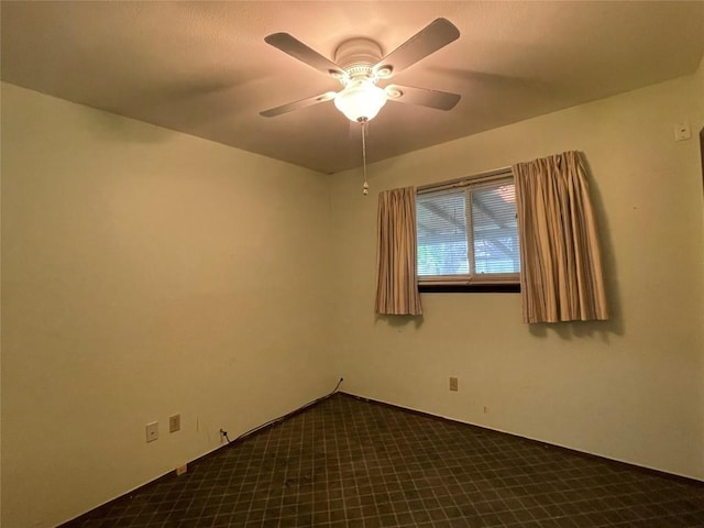 unfurnished room with dark carpet and a ceiling fan