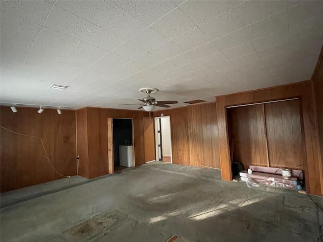 interior space featuring ceiling fan, visible vents, and wood walls