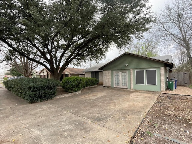 ranch-style home with french doors, brick siding, and fence