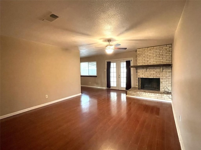 unfurnished living room featuring visible vents, a ceiling fan, wood finished floors, a fireplace, and baseboards