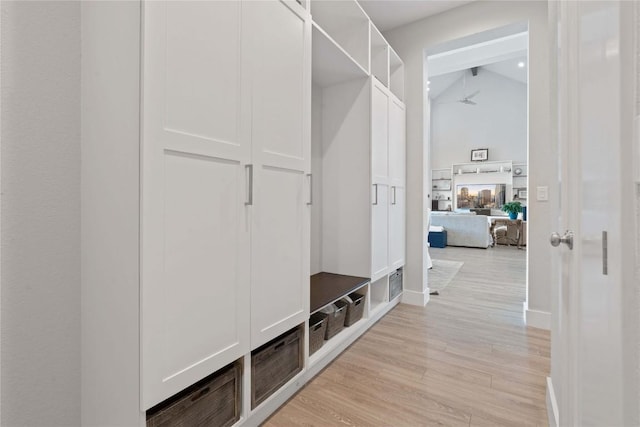 mudroom featuring baseboards, light wood-style floors, and vaulted ceiling