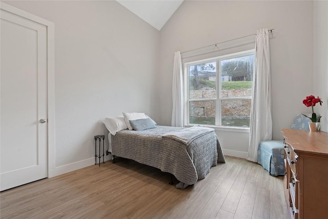 bedroom featuring vaulted ceiling, baseboards, and light wood-type flooring