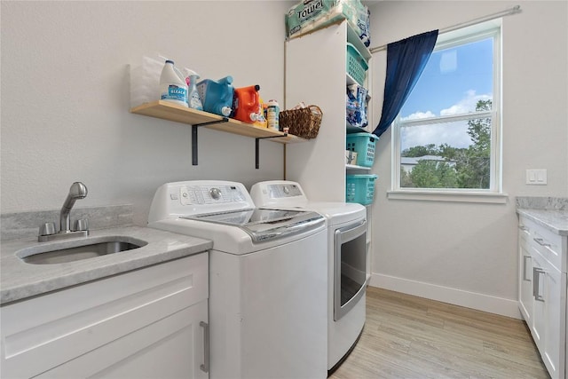 laundry room with a sink, light wood-style floors, baseboards, and separate washer and dryer