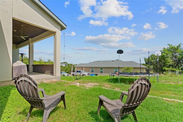 view of yard featuring a trampoline, ceiling fan, and a patio area