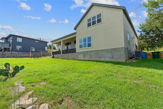 back of house featuring central air condition unit, a yard, stucco siding, and fence