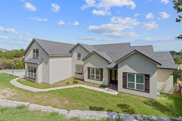 modern farmhouse style home with a front lawn, stucco siding, and a shingled roof